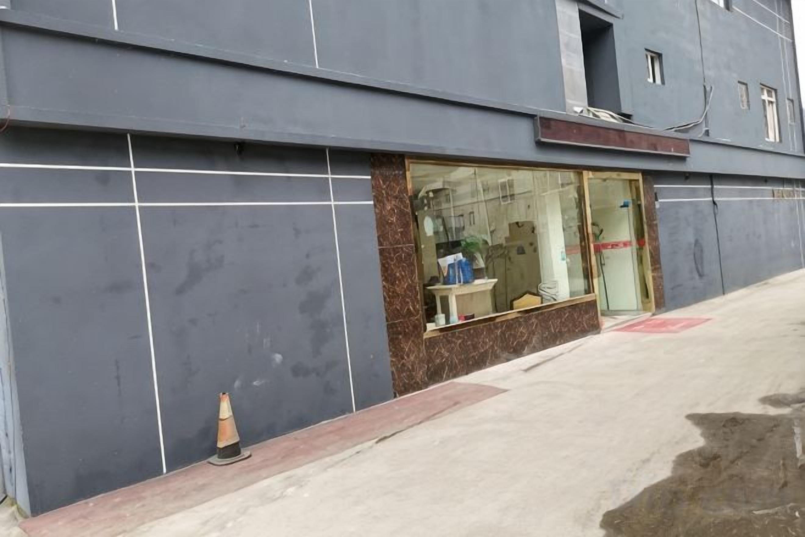 A building facade with large windows, a visible entrance, and a small traffic cone on the sidewalk.