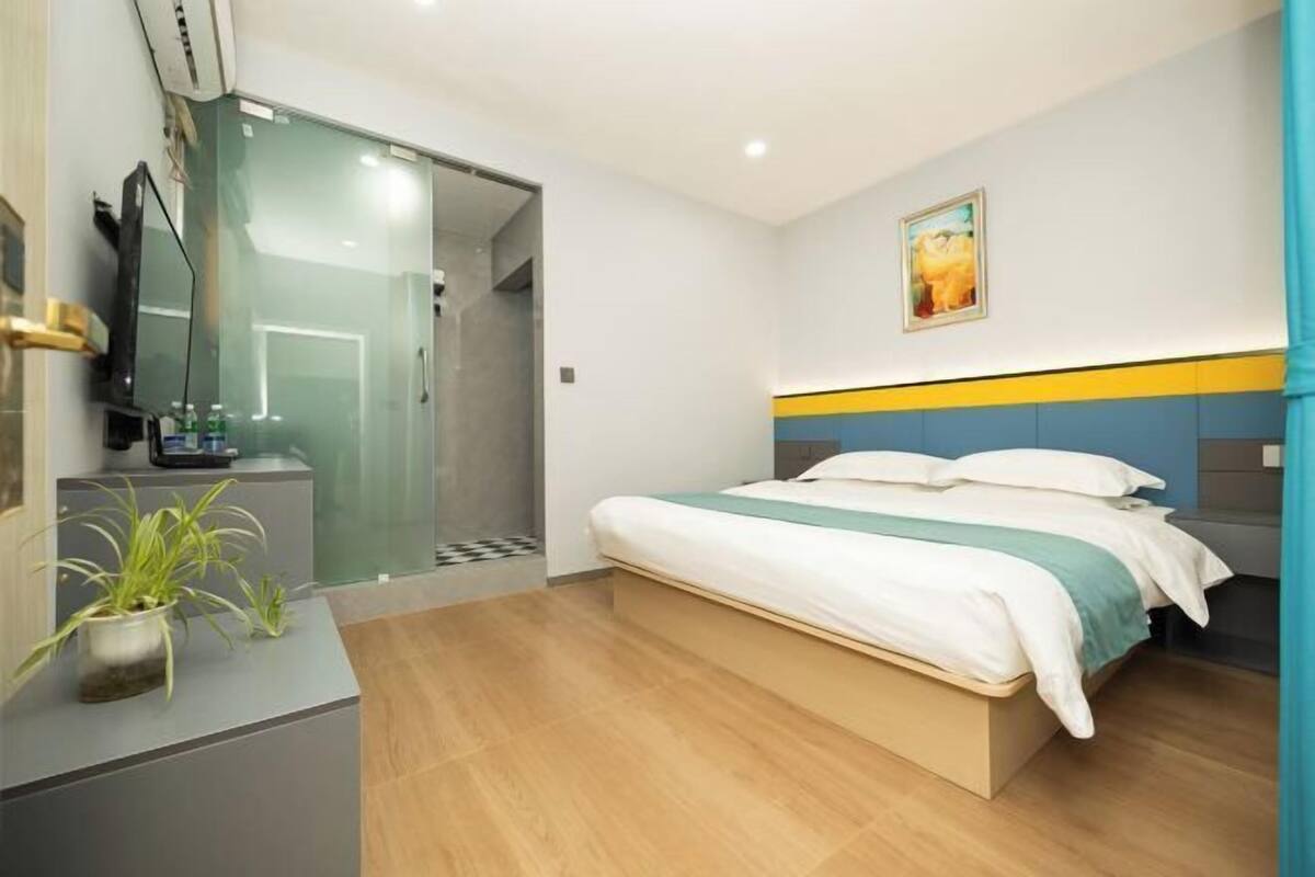 A modern hotel room with a bed, bedside table, and a small potted plant.