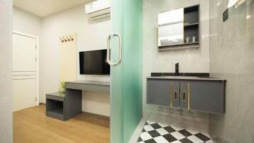 A modern bathroom with a black and white checkered floor, a grey vanity with a mirror, and a wall-mounted TV.