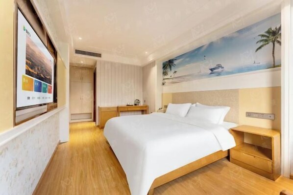 A hotel room with a large bed, a desk, and a painting of a beach scene.