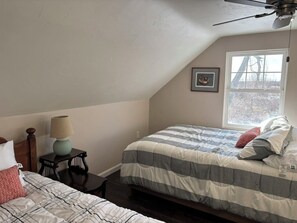 A bedroom with two beds, a ceiling fan, a window, and a framed picture on the wall. - Spacious waterfront home recently remodeled with WiFi, AC, and cable TV. (Oconto)
