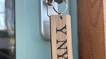 Een houten sleutelhanger met de naam 'HILAN' eraan bevestigd aan een deurklink.