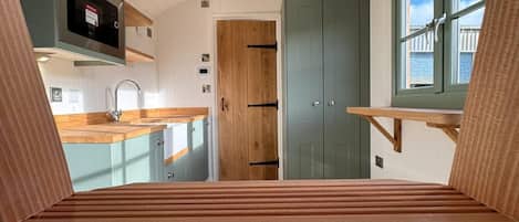 A modern kitchen with wooden cabinetry, a built-in oven, and a window overlooking a balcony.