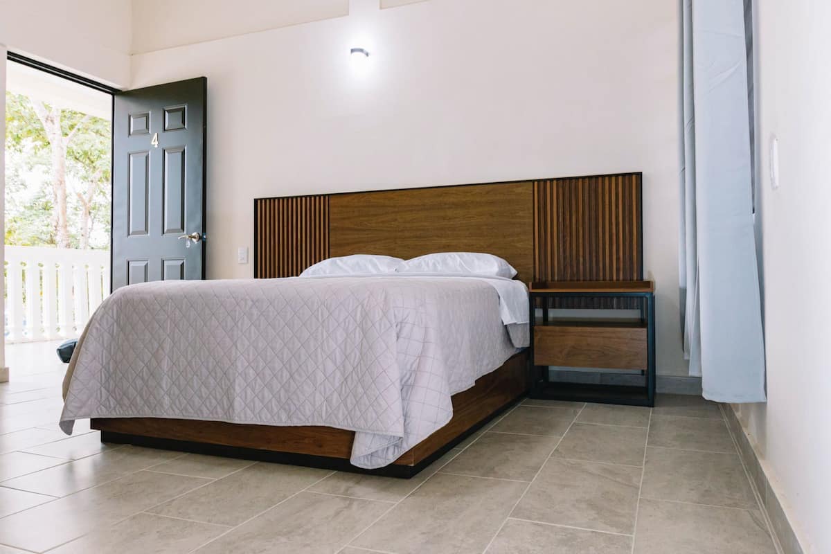 Un dormitorio con cama, mesita de noche y puerta.