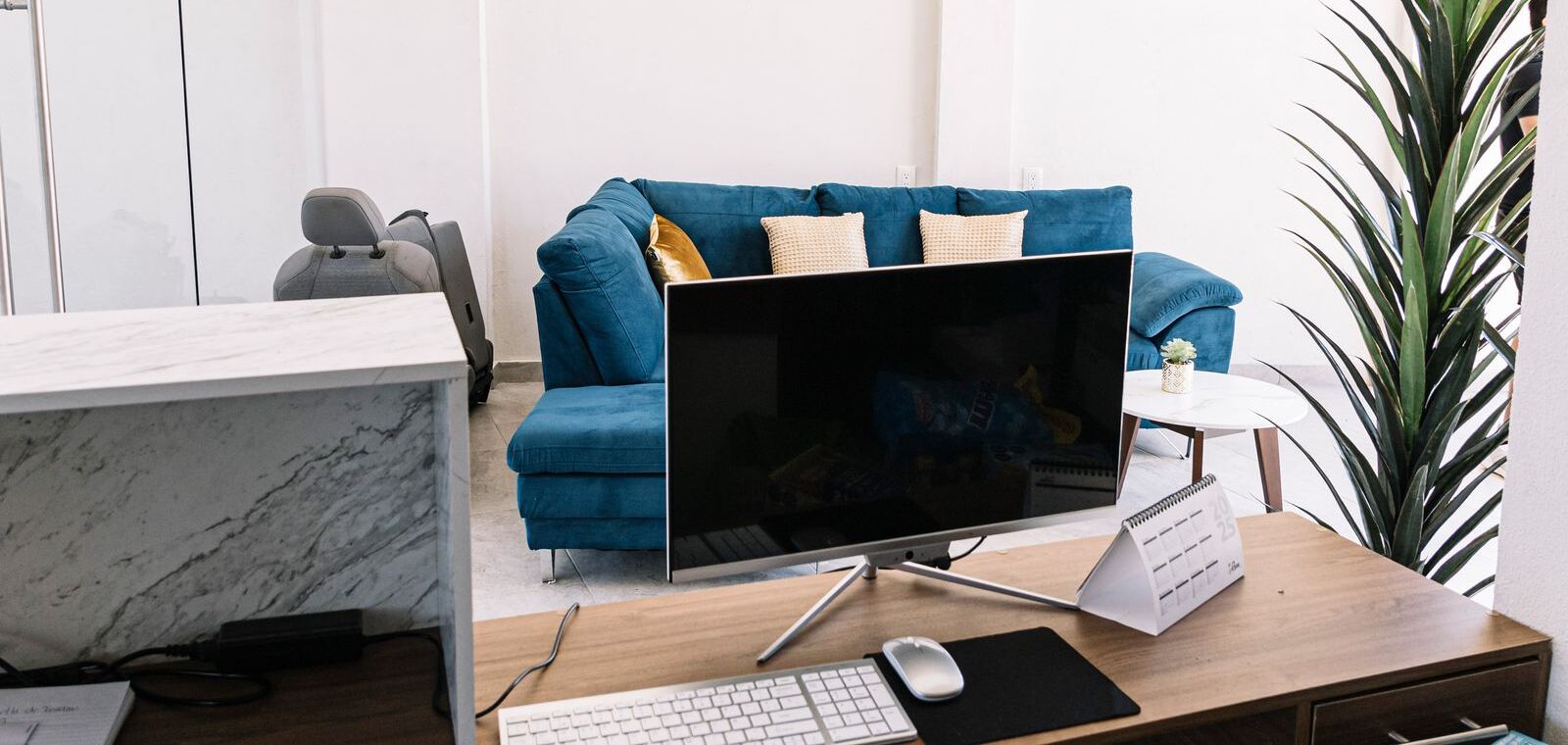 Un bureau moderne aménagé pour le télétravail, avec un bureau, un ordinateur et un canapé bleu.