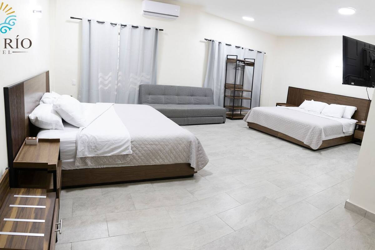 Habitación de hotel con dos camas, un sofá, un televisor y un armario.