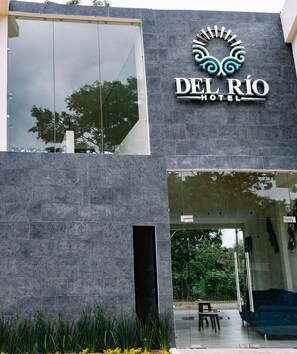 The exterior of Del Rio Hotel with a modern design, large glass windows, and a stone facade. - DEL RIO HOTEL (Axtla de Terrazas)