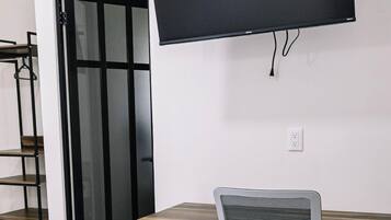Ett modernt kontorsutrymme med ett skrivbord, en stol och en väggmonterad platt-TV.