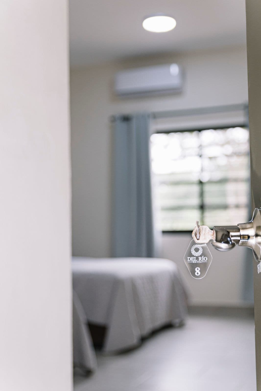 Une chambre d’hôtel avec un lit, une fenêtre avec des rideaux et un appareil de climatisation fixé au mur.
