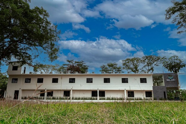 Un hôtel moderne doté d’un toit plat, de nombreuses fenêtres et d’une enseigne indiquant « HÔTEL DEL RÍO ».