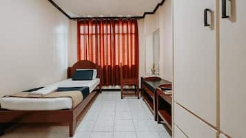 Un dormitorio con cama, escritorio, silla y ventana con cortinas.
