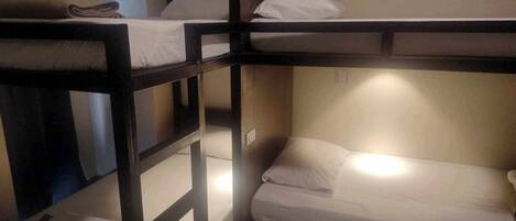 A bunk bed room with two beds, each with a pillow and a folded blanket.
