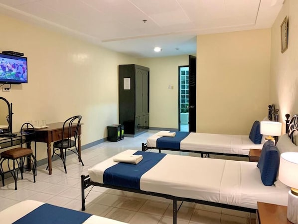 A hotel room with two beds, a desk with chairs, a television, and a cabinet. - Fuente Hotel De Cebu (Cebu City)