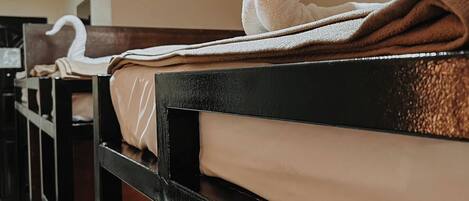 Bunk beds with white sheets and a swan-shaped towel on the headboard.
