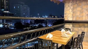 Ein Balkon mit Steinmauer und Blick auf nächtliche Stadtgebäude.