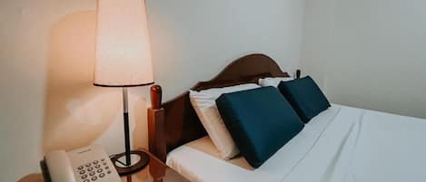 Une chambre d’hôtel avec un lit, une lampe de chevet et un téléphone sur une table de chevet.