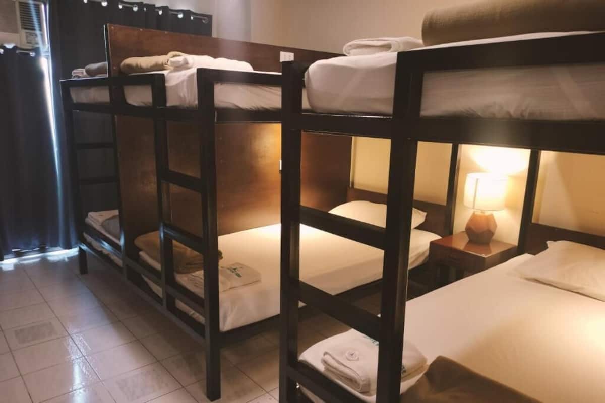 Des lits superposés dans une chambre avec un sol carrelé et une table de chevet avec une lampe.