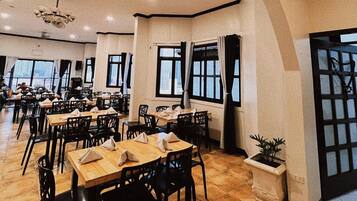 A spacious restaurant with high ceilings, multiple dining tables, and chairs.