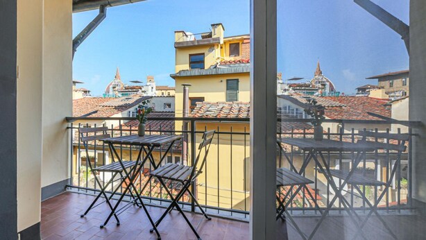 A balcony with a view of buildings and a church steeple.