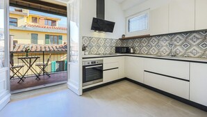 A kitchen with white cabinets, a black microwave, and a patterned backsplash.