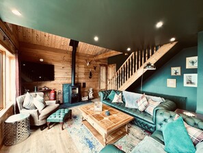 Ein gemütliches Wohnzimmer mit Holzvertäfelung, einer Sofagarnitur, einem Couchtisch und einer Treppe.