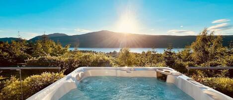 A hot tub with a clear view of a lake and mountains in the background.
