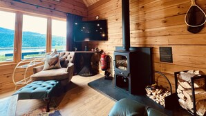 Ein gemütliches Blockhaus-Interieur mit Kamin, bequemen Sitzmöglichkeiten, einem Fernseher und schöner Aussicht.