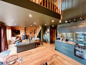 Una sala de estar acogedora con sofá, una mesa de comedor y una zona de cocina con armarios y electrodomésticos.