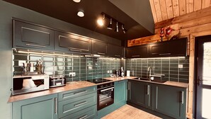Eine moderne Küche mit dunkel-türkisfarbenen Schränken, einer Holz Arbeitsplatte und einem eingebauten Backofen.