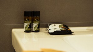 A bathroom with a white bathtub, two bottles of olive care shower gel, and a black toiletry bag. - Private Room 2, with S.Peter View (Irnerio) (Roma)