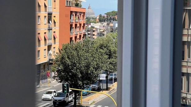 A view of a city street with buildings, a tree, and a traffic light. - Private Room 2, with S.Peter View (Irnerio) (Roma)