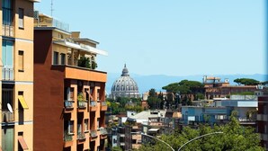 A multi-story building with balconies, a dome structure in the background, and a clear sky. - Private Room 2, with S.Peter View (Irnerio) (Roma)