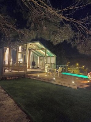 A glass-enclosed structure with a patio area, outdoor seating, and a swimming pool. - La Dacha Montanya (Seva)
