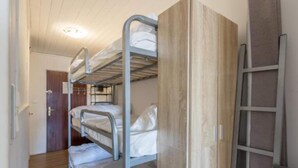 Ein Schlafzimmer mit Etagenbetten, einem Holzschrank und einer Leiter.