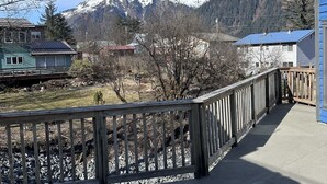 Una terraza de madera con vistas a montañas nevadas al fondo.
