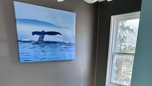 Una habitación con un ventanal grande, un ventilador de techo y un estante en la pared.