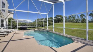 A swimming pool with a glass enclosure, surrounded by lounge chairs and a view of a grassy area. - Highlands Reserve 4 Bed Pool Home with Spa - Golf Course Views (Davenport)