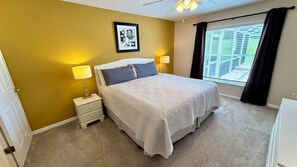 A bedroom with a bed, two bedside lamps, a nightstand, a framed picture on the wall, and a window with curtains. - Highlands Reserve 4 Bed Pool Home with Spa - Golf Course Views (Davenport)