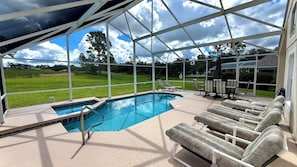 An outdoor swimming pool with lounge chairs and a covered area, surrounded by a fence and trees. - Highlands Reserve 4 Bed Pool Home with Spa - Golf Course Views (Davenport)