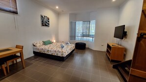A compact bedroom with a bed, a desk, a television, and a window with blinds. - SandNSea - Only Steps to the beach -Pet Friendly Accommodation (Burrum Heads)