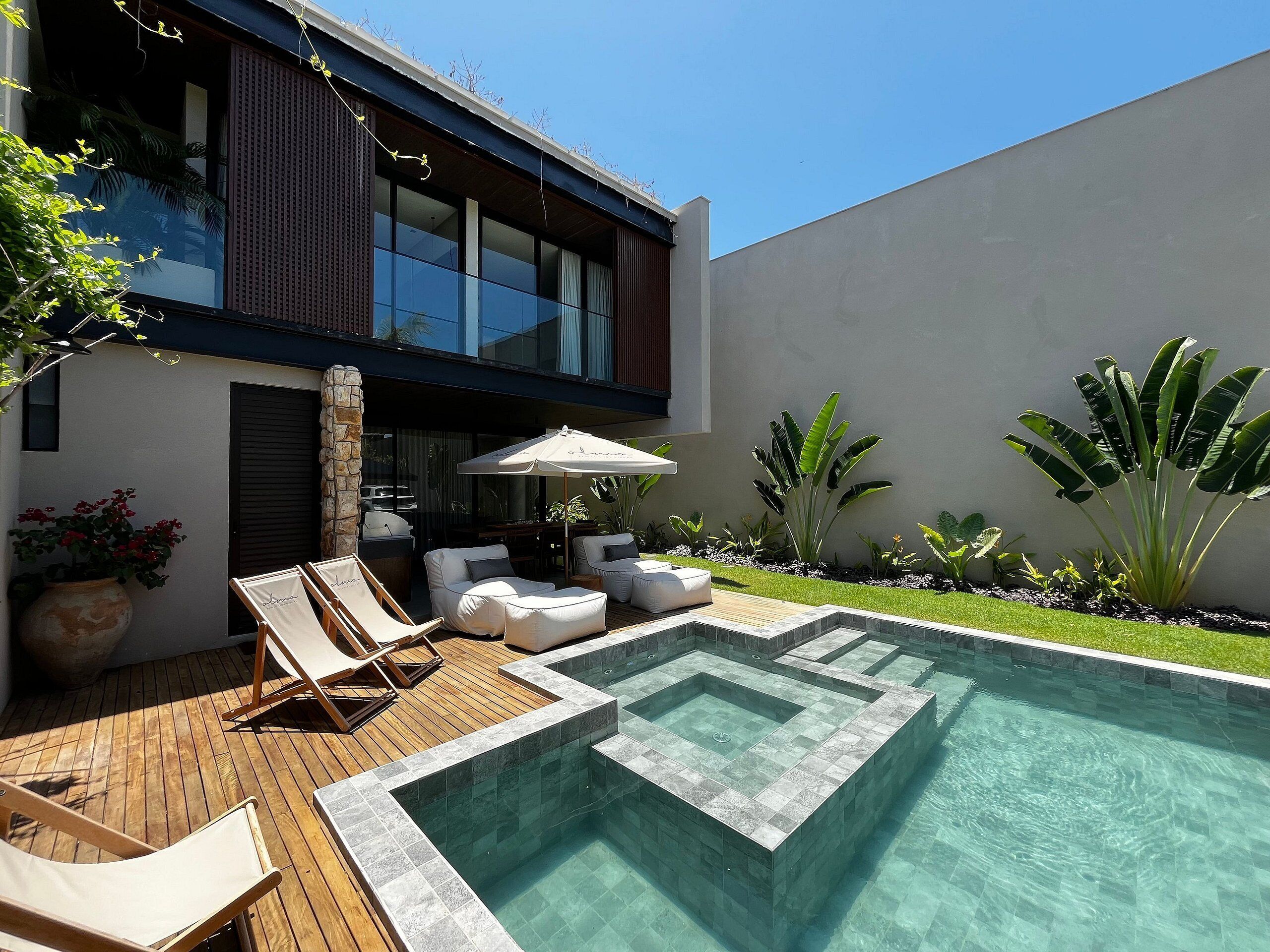 A modern outdoor pool area with a geometric design, surrounded by a wooden deck and lounge chairs.
