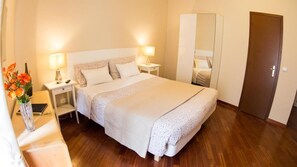 A neatly arranged hotel room with a large bed, bedside lamps, a wardrobe, and a wooden floor. - hotel martino ai monti (Rome)