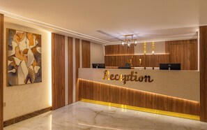 A reception desk with a marble floor, wooden paneling, and a wall-mounted painting. - MEDAD ALSHATEA SERVICED APARTMENTS (Dammam)