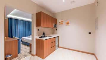 Una habitación de hotel compacta con kitchenette, cama, zona de estar y baño.
