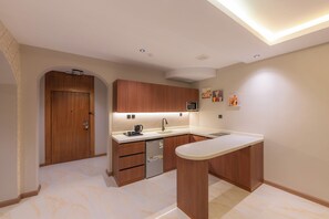 A modern kitchen with wooden cabinets, a built-in dishwasher, and a white countertop. - MEDAD ALSHATEA SERVICED APARTMENTS (Dammam)