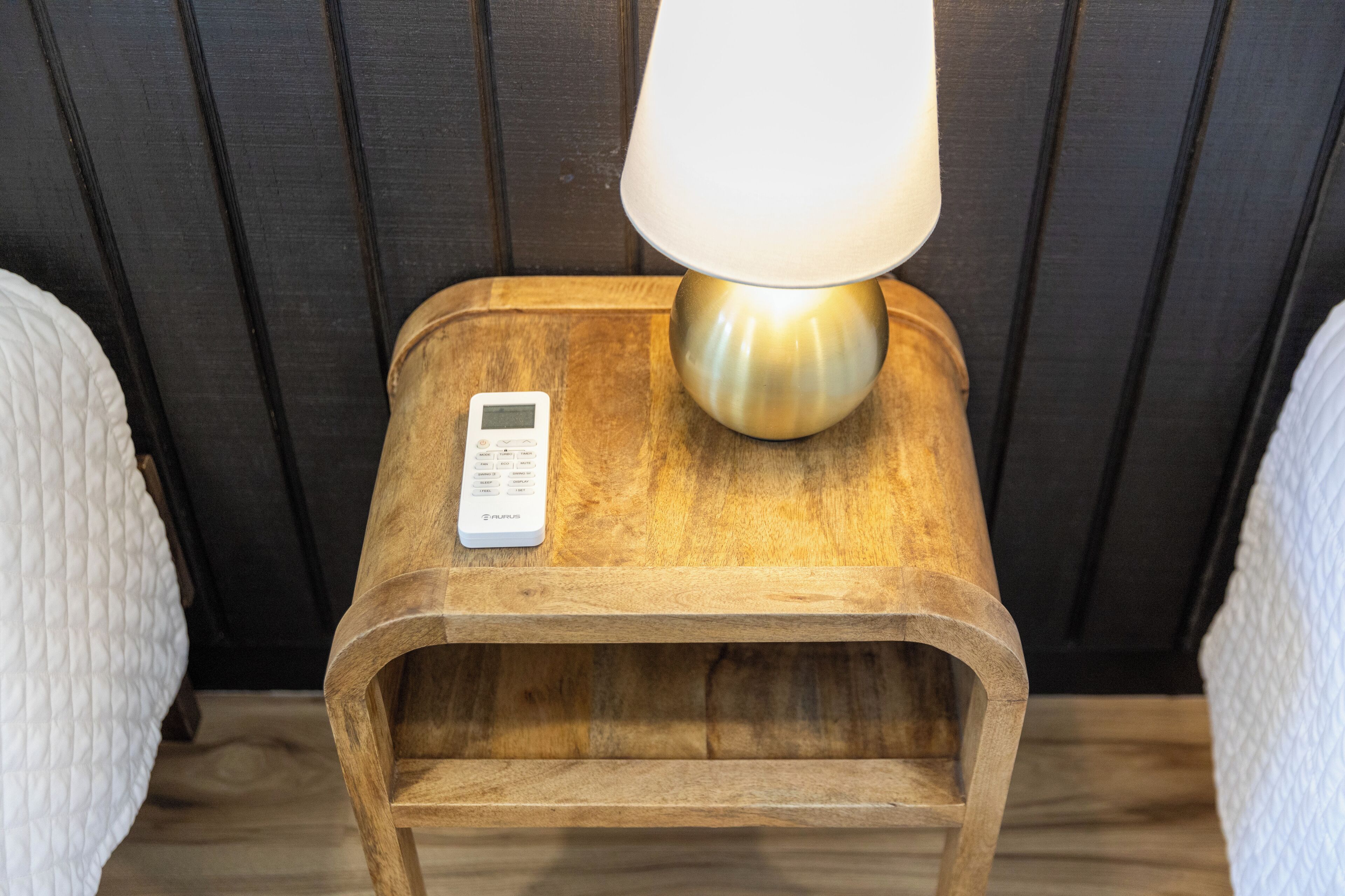 A wooden bedside table with a lamp and a digital clock.