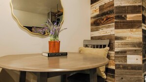 Une table ronde sur laquelle repose un livre intitulé « Jane Eyre » et un pot de fleurs contenant une plante aux fleurs violettes.