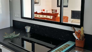 A kitchen with a large window, a sink, and a countertop with various items.