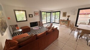 A living room with a sofa, TV, and dining area with chairs and a table.