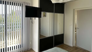 A modern bedroom with a bed, a TV mounted on the wall, and a sliding door closet.